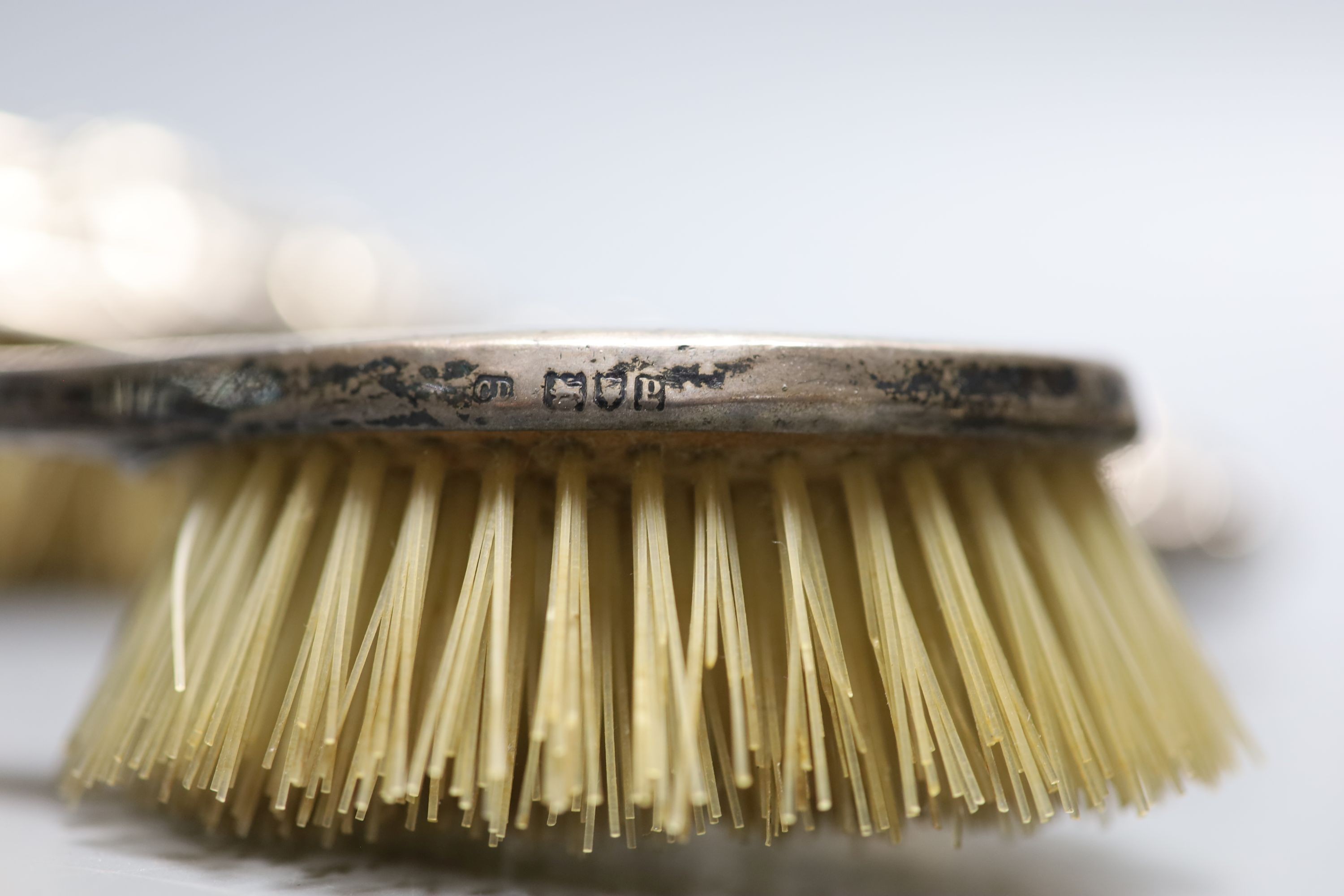 A pair of Edwardian repousse silver backed hair brushes and two other brushes.